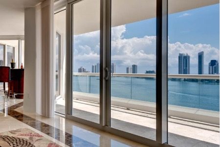 Modern interior with double glass doors showcasing Miami Beach skyline and waterfront view, relevant to economic development and business insights.